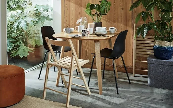 Round oak dining table with mixed folding and shell chairs.
