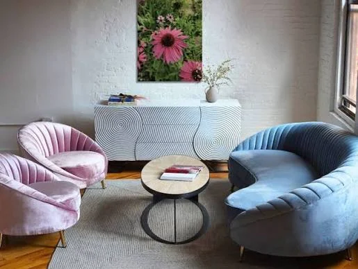Channel-tufted blue velvet upholstery on a curved sofa.